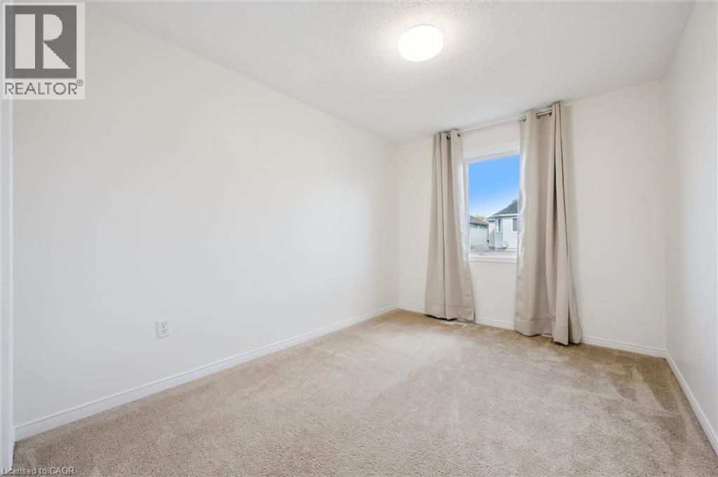 Carpeted flooring, white painted walls, window with trim, and a ceiling-mounted light fixture - 151 Clairfields Drive Unit# 3, Guelph, ON