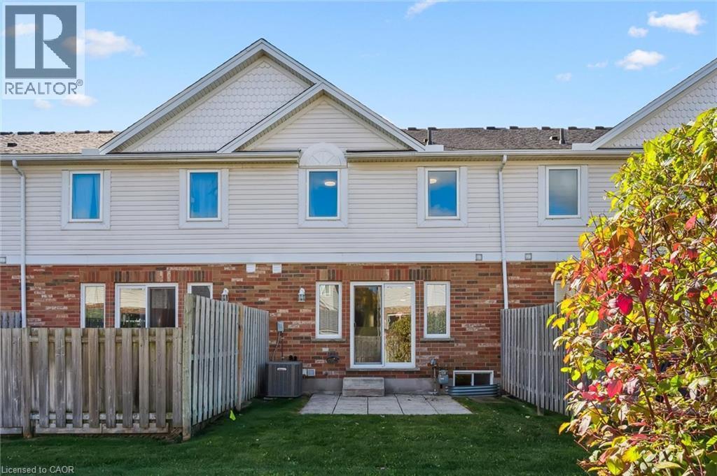 Rear exterior with brick and siding facade, patio, and fenced yard - 151 Clairfields Drive Unit# 3, Guelph, ON