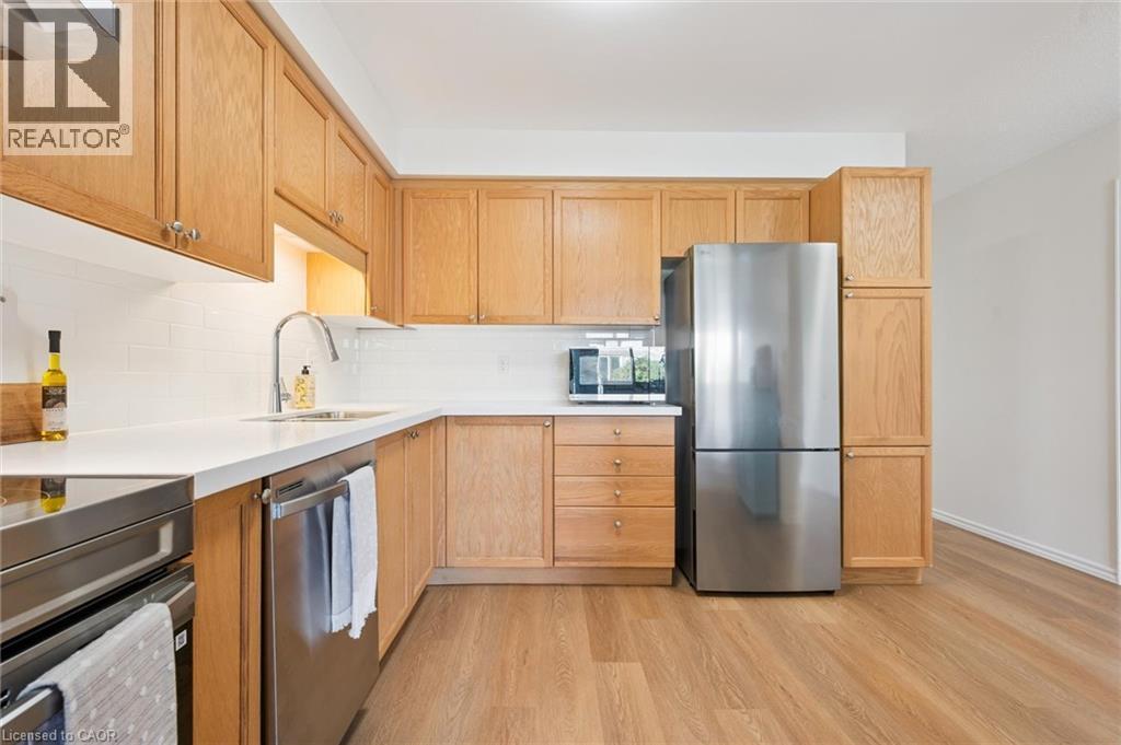 Kitchen featuring wood-finish cabinetry, white countertops, stainless steel appliances, and wood-finish flooring - 151 Clairfields Drive Unit# 3, Guelph, ON