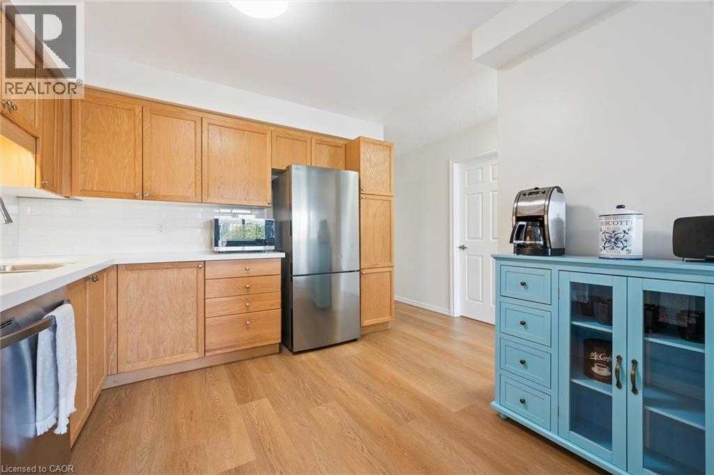 Wood-finish flooring, light wood cabinetry, white subway tile backsplash, white countertops, and stainless steel appliances - 151 Clairfields Drive Unit# 3, Guelph, ON