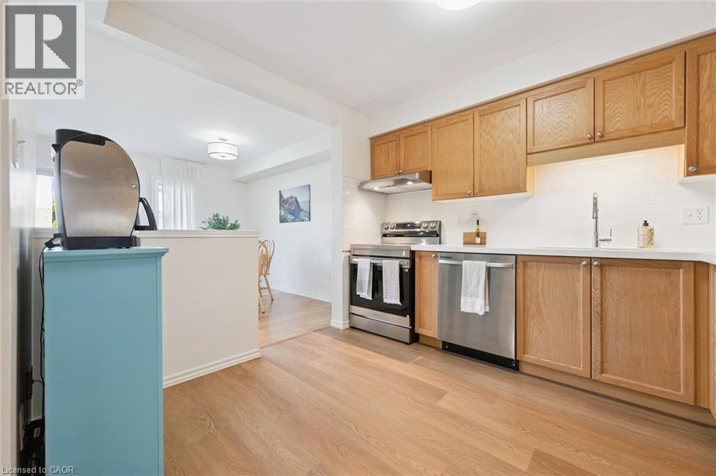 Kitchen featuring wood-finish flooring, light wood cabinetry, stainless steel appliances, white subway tile backsplash, and light-toned countertops - 151 Clairfields Drive Unit# 3, Guelph, ON