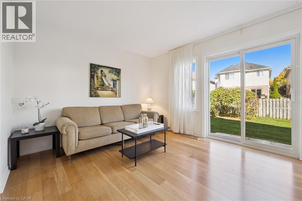 Hardwood-style flooring throughout, with a large sliding glass door opening to a private green space - 151 Clairfields Drive Unit# 3, Guelph, ON