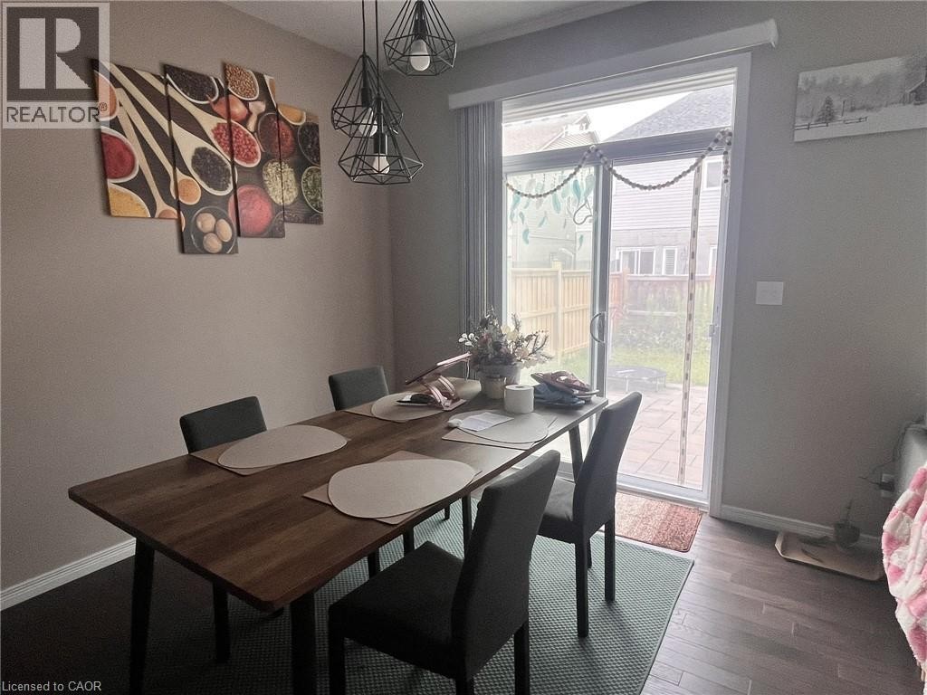 Sliding glass door leading to outdoor space, dark wood-finish flooring, and a contemporary multi-bulb light fixture - 298 Buttonbush Street, Waterloo, ON