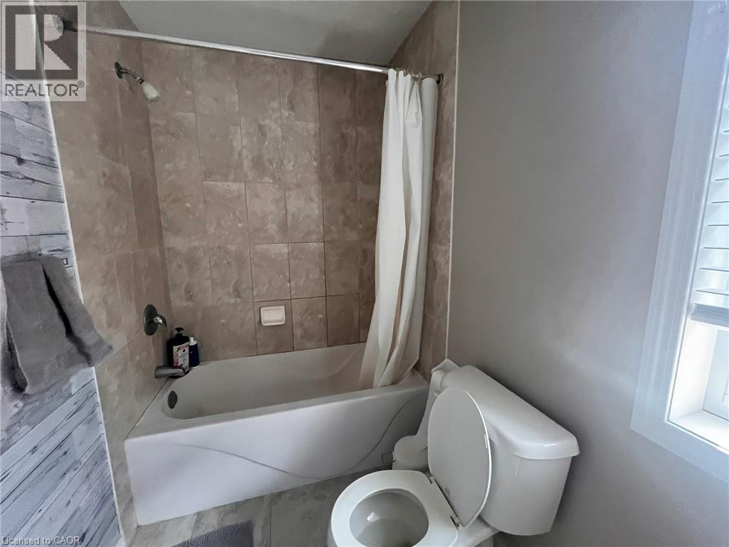 Bathtub with a shower, tiled shower surround, and a toilet - 298 Buttonbush Street, Waterloo, ON