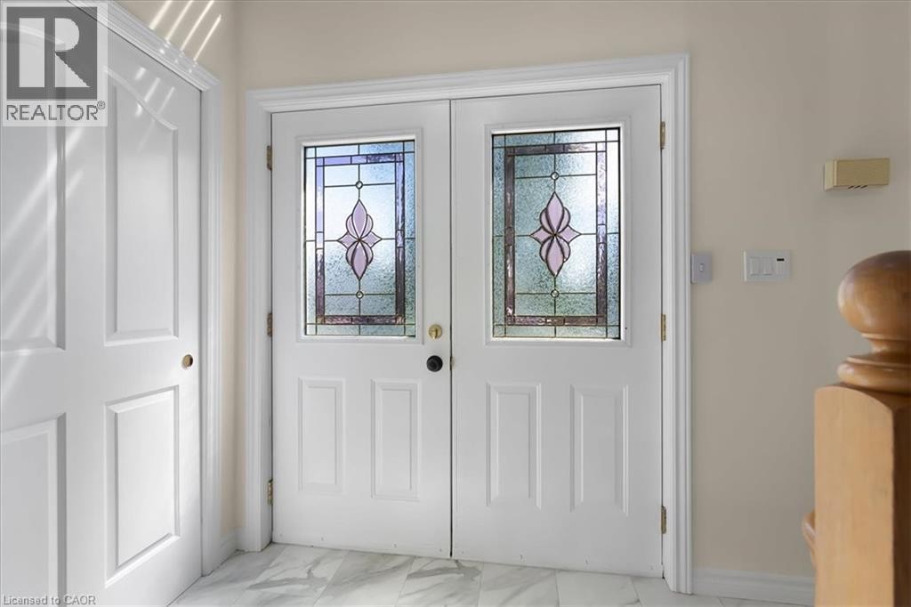 Double entry doors with decorative stained glass panels, set on a light-toned tile floor - 150 Bankside Drive, Kitchener, ON