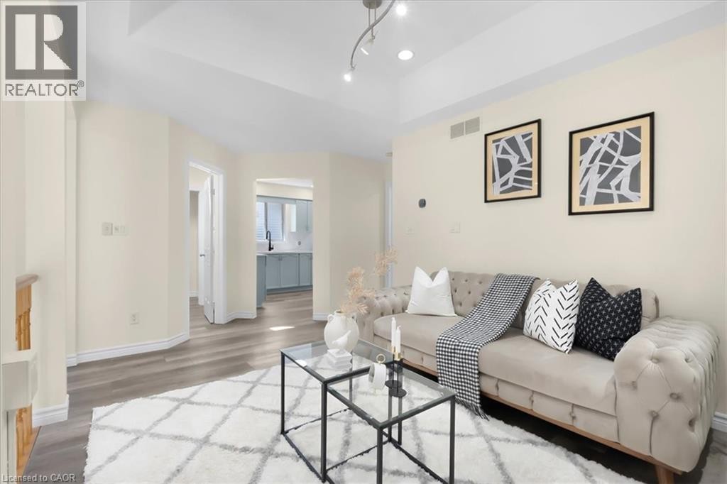 Bright, open living space featuring wood-finish flooring, recessed ceiling lighting, and track lighting - 150 Bankside Drive, Kitchener, ON