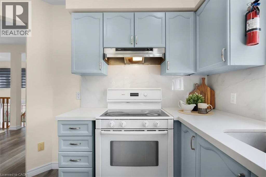 Light blue cabinetry with silver-tone hardware, white countertops, and a white tile backsplash - 150 Bankside Drive, Kitchener, ON