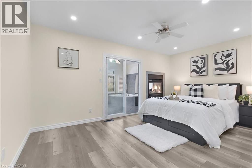 Wood-finish flooring, recessed lighting, ceiling fan, built-in fireplace, and sliding glass door - 150 Bankside Drive, Kitchener, ON