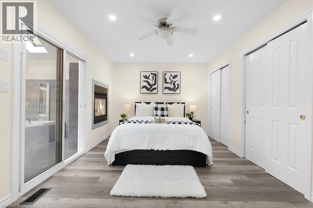 Wood-finish flooring, recessed lighting, ceiling fan, built-in fireplace, and sliding glass door - 150 Bankside Drive, Kitchener, ON