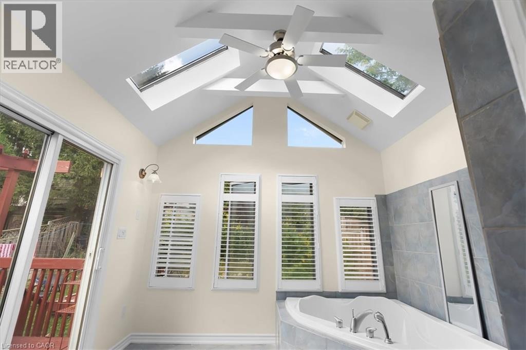 Vaulted ceiling with exposed beams, multiple skylights, and a ceiling fan - 150 Bankside Drive, Kitchener, ON