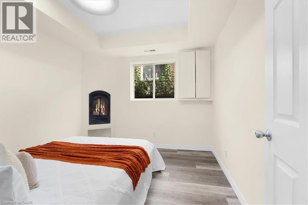 Gas fireplace, wood-finish flooring, white walls, built-in cabinetry, and white paneled door - 150 Bankside Drive, Kitchener, ON