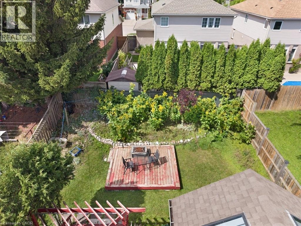 Expansive backyard featuring a wood deck, manicured lawn, and privacy fencing - 150 Bankside Drive, Kitchener, ON