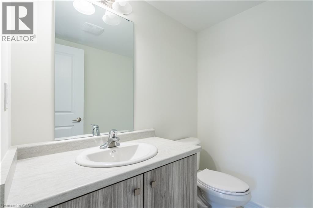 Vanity with a surface-mounted sink, chrome faucet, wood-finish cabinetry, and an overhead light fixture - 23 Dryden Lane, Hamilton, ON