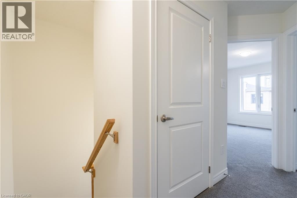 White paneled doors with brushed nickel hardware, light wood handrail, and light gray carpeted flooring - 23 Dryden Lane, Hamilton, ON