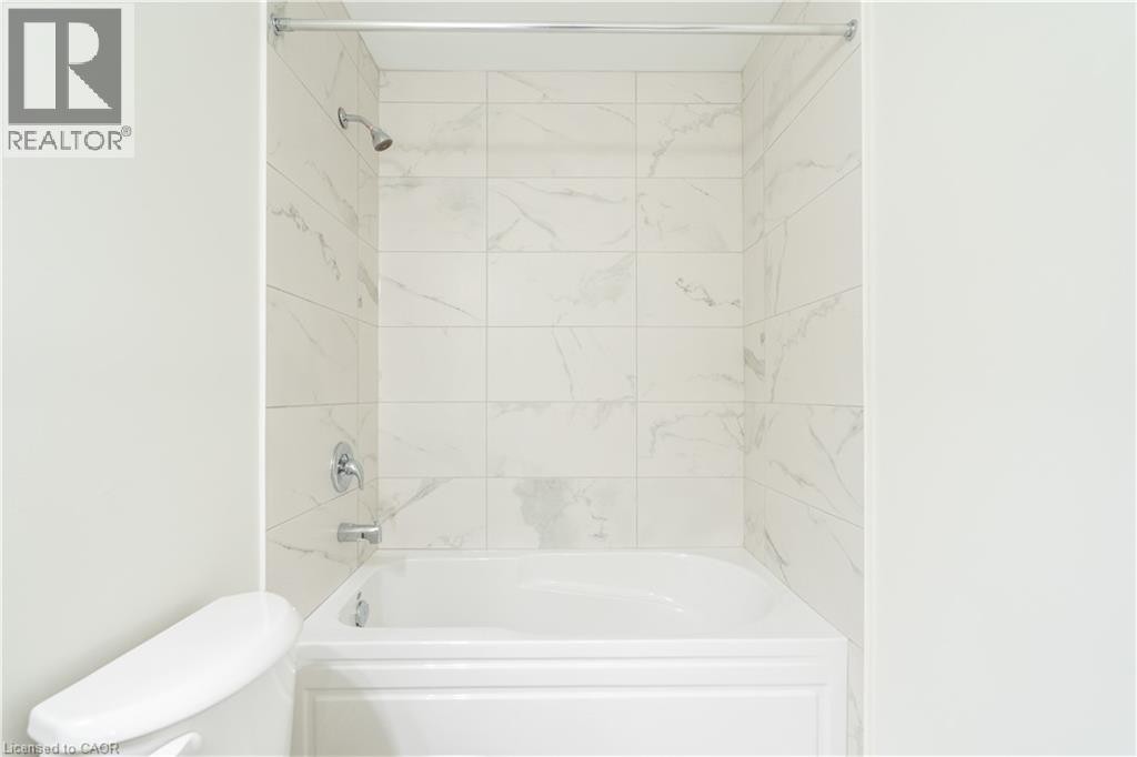 White bathtub with chrome fixtures and polished chrome shower rod - 23 Dryden Lane, Hamilton, ON