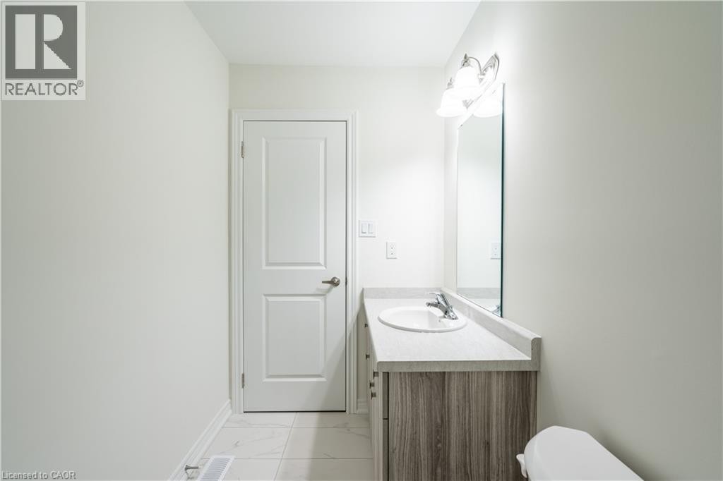 Modern bathroom featuring a wood-finish vanity with an integrated rectangular sink, chrome faucet, and ample counter space - 23 Dryden Lane, Hamilton, ON