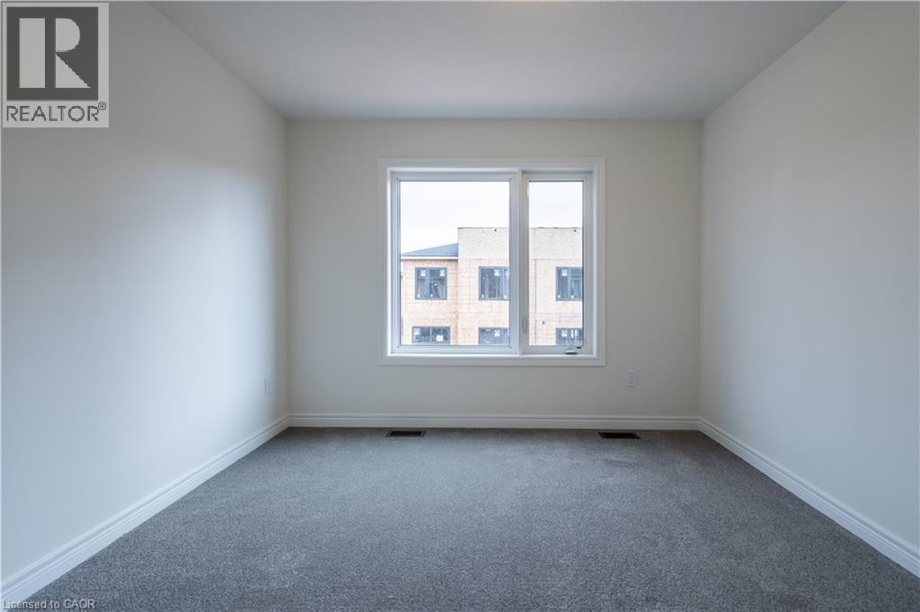 Bright corner bedroom featuring neutral wall finishes, neutral-tone carpet flooring, and a large dual-pane window with natural light exposure overlooking the surrounding streetscape - 23 Dryden Lane, Hamilton, ON