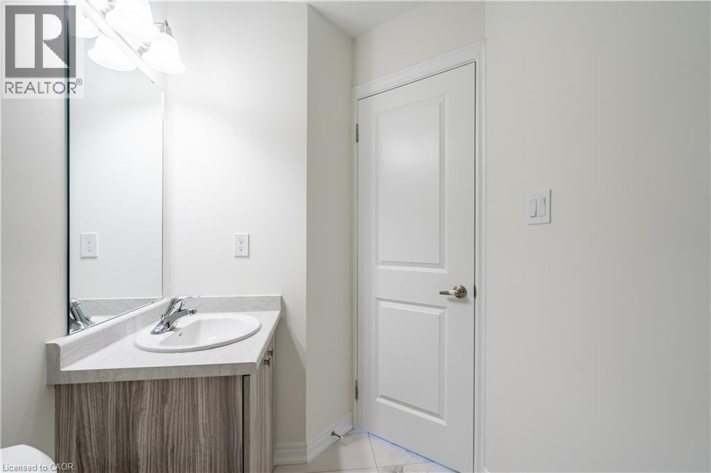 Vanity with wood-finish cabinetry, integrated sink, and light-toned countertop - 23 Dryden Lane, Hamilton, ON