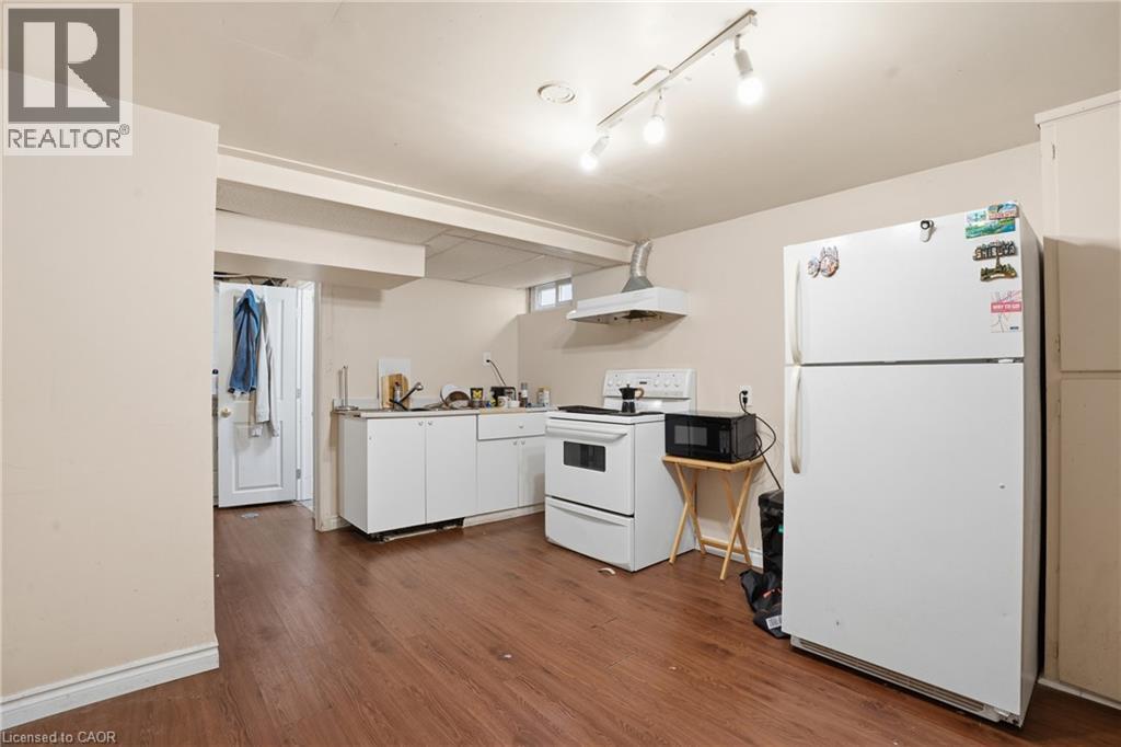 Kitchen area featuring wood-finish flooring, white cabinetry, track lighting, and a window - 139 Dalewood Avenue, Hamilton, ON