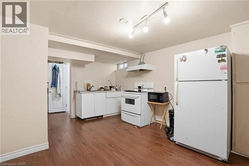 Kitchen area featuring wood-finish flooring, white cabinetry, track lighting, and a window - 139 Dalewood Avenue, Hamilton, ON 