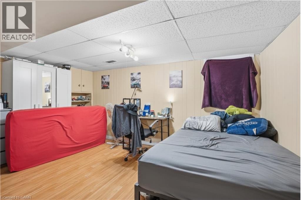 Versatile room featuring wood-finish flooring, drop ceiling with recessed lighting, and light-toned wall paneling - 139 Dalewood Avenue, Hamilton, ON