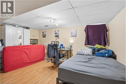 Versatile room featuring wood-finish flooring, drop ceiling with recessed lighting, and light-toned wall paneling - 139 Dalewood Avenue, Hamilton, ON 