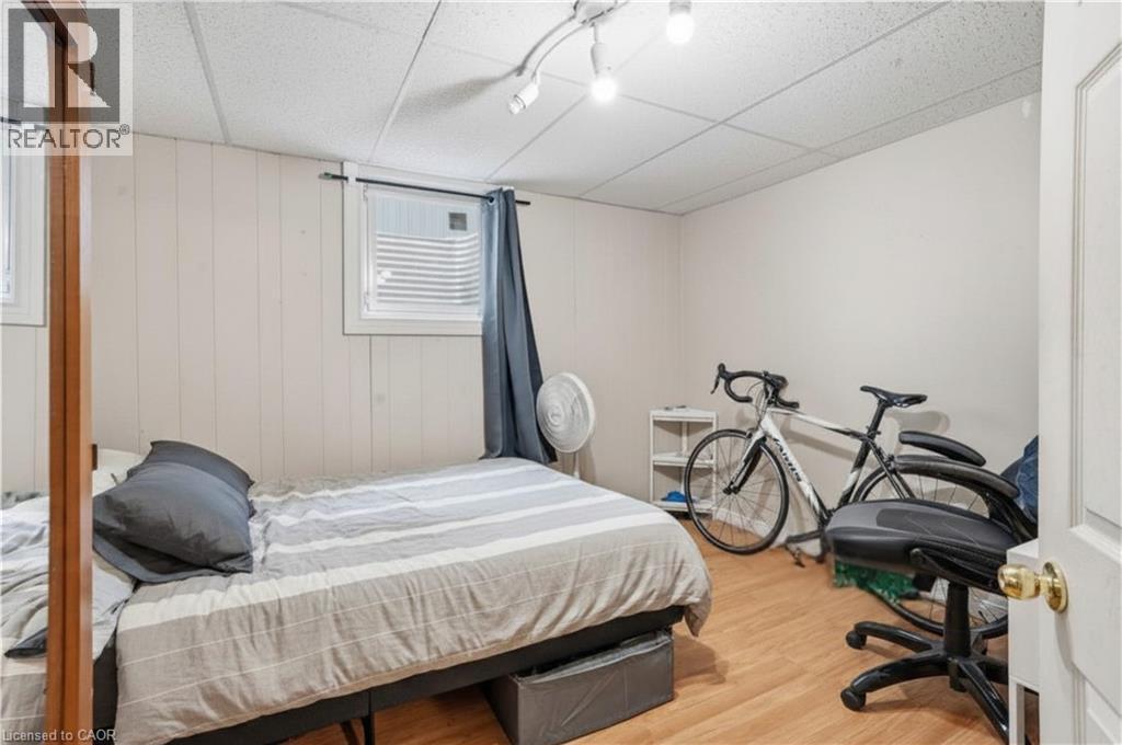 Room featuring wood-finish flooring, white paneled walls, and a drop ceiling with track lighting - 139 Dalewood Avenue, Hamilton, ON