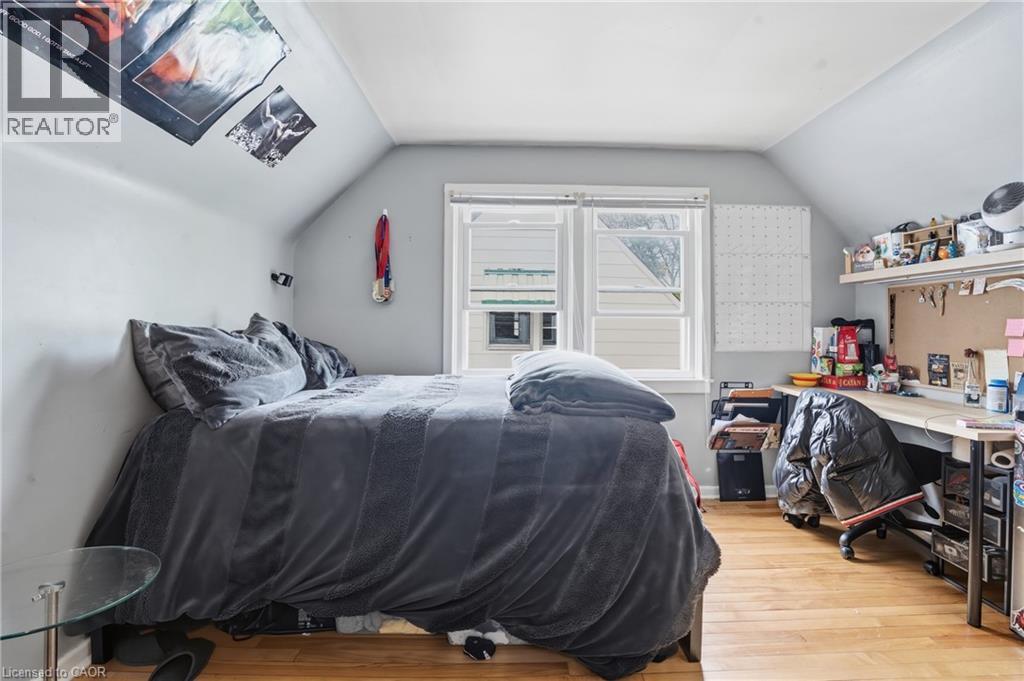 Bedroom featuring a window with white trim, light gray walls, and wood-finish flooring - 139 Dalewood Avenue, Hamilton, ON