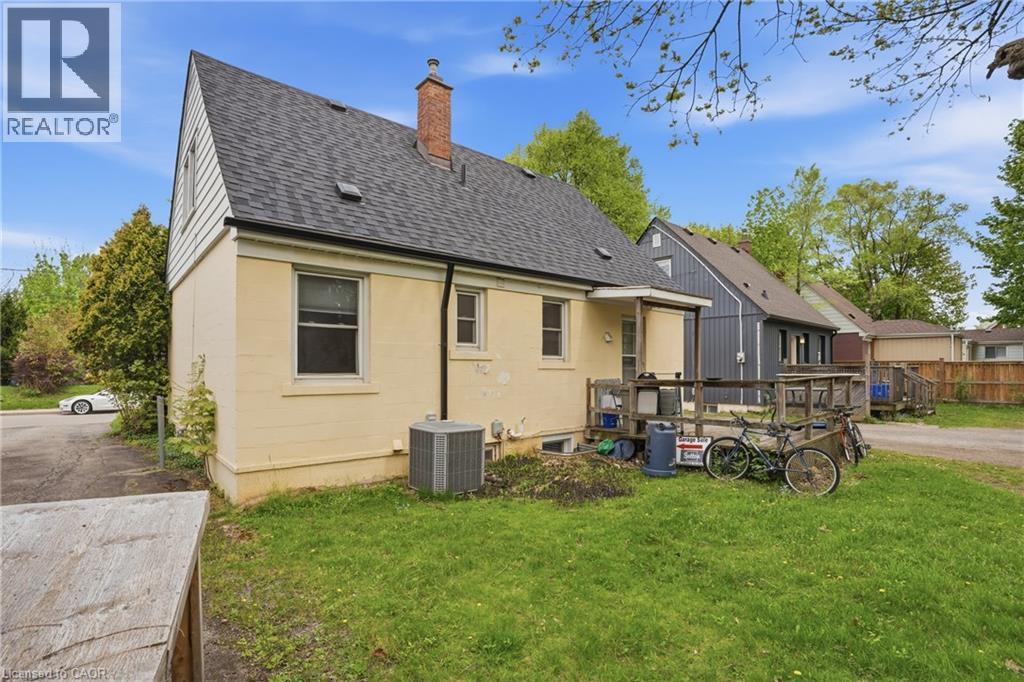 Rear exterior featuring a covered porch, brick chimney, and a gravel driveway - 139 Dalewood Avenue, Hamilton, ON