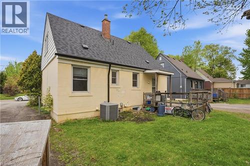 Rear exterior featuring a covered porch, brick chimney, and a gravel driveway - 139 Dalewood Avenue, Hamilton, ON 