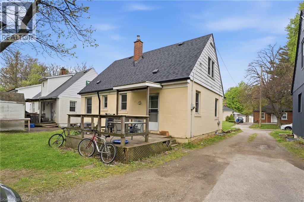 Rear exterior showcasing a raised wooden deck, a light-colored brick facade, and a dark shingle roof - 139 Dalewood Avenue, Hamilton, ON