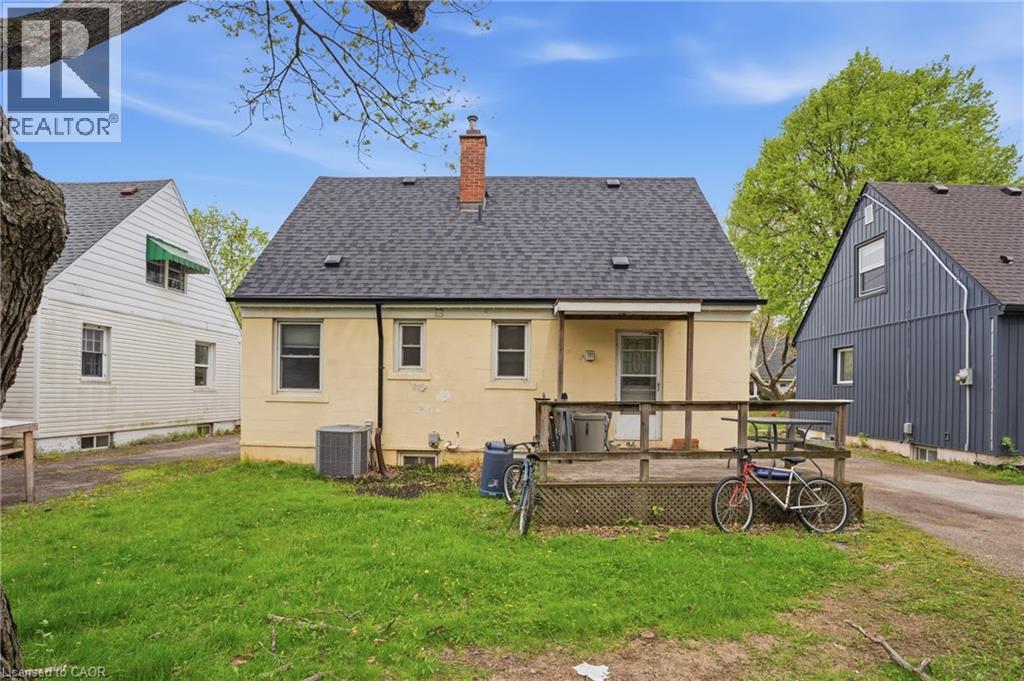 Rear exterior featuring a wood deck, asphalt shingle roof, and brick chimney - 139 Dalewood Avenue, Hamilton, ON