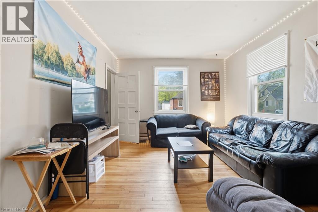 Luminous living area featuring wood-finish flooring, multiple windows with blinds, and light-toned wall finishes - 139 Dalewood Avenue, Hamilton, ON