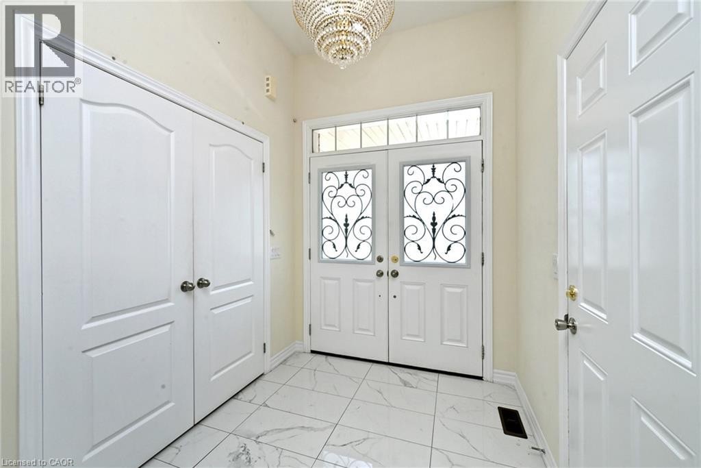 Double entry doors with decorative wrought iron inserts, transom window, recessed double-door closet, and large-format tile flooring - 64 Maple Cider Street, Caledon, ON