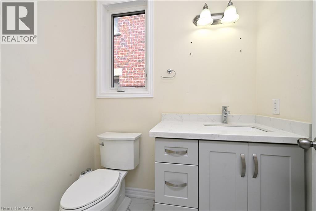 Corner vanity with stone-finish countertop and integrated sink, chrome faucet, and gray cabinetry with brushed nickel hardware - 64 Maple Cider Street, Caledon, ON