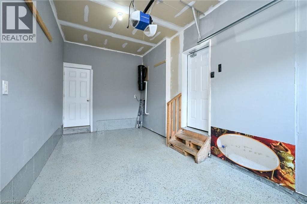 Attached garage with light gray painted walls and a speckled epoxy floor - 64 Maple Cider Street, Caledon, ON