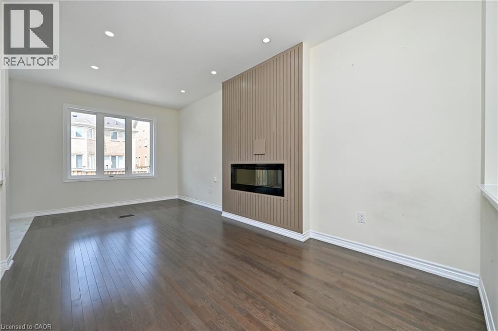 Recessed lighting, wood-finish flooring, a linear electric fireplace, and a large three-panel window - 64 Maple Cider Street, Caledon, ON