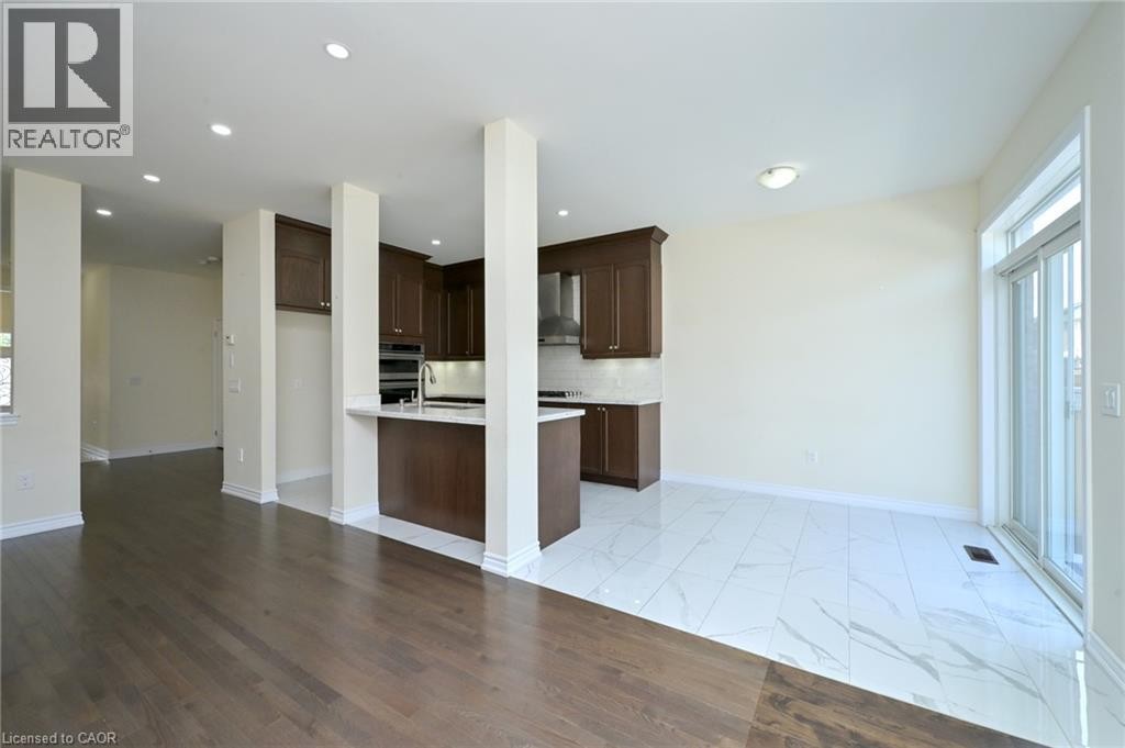 Dark wood-finish flooring, white tile flooring, recessed lighting, brown wood cabinetry, and a stainless steel range hood - 64 Maple Cider Street, Caledon, ON