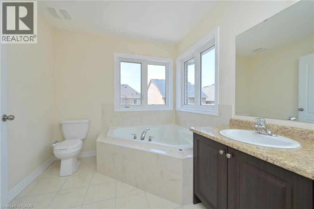 Alcove bathtub with corner windows, single vanity with an integrated sink, built-in mirror, and tile flooring - 64 Maple Cider Street, Caledon, ON