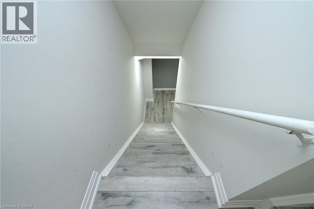 Stairway featuring wood-finish flooring, light wall tones, and a wall-mounted handrail - 64 Maple Cider Street, Caledon, ON