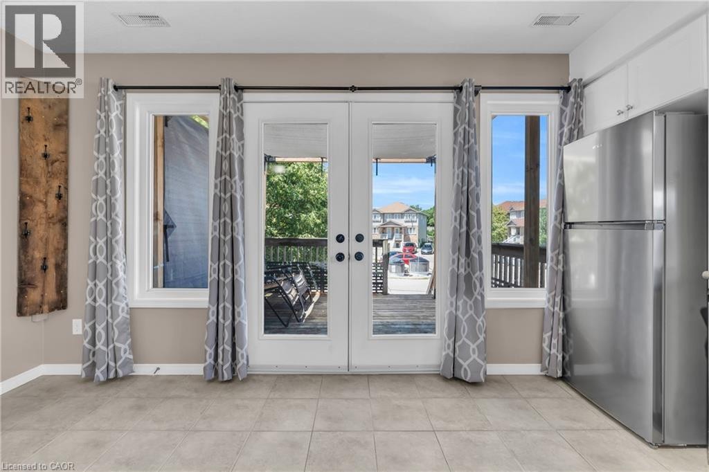 Dual French doors flanked by windows, tile flooring, and integrated stainless steel refrigerator - 50 Howe Drive Unit# 19B, Kitchener, ON