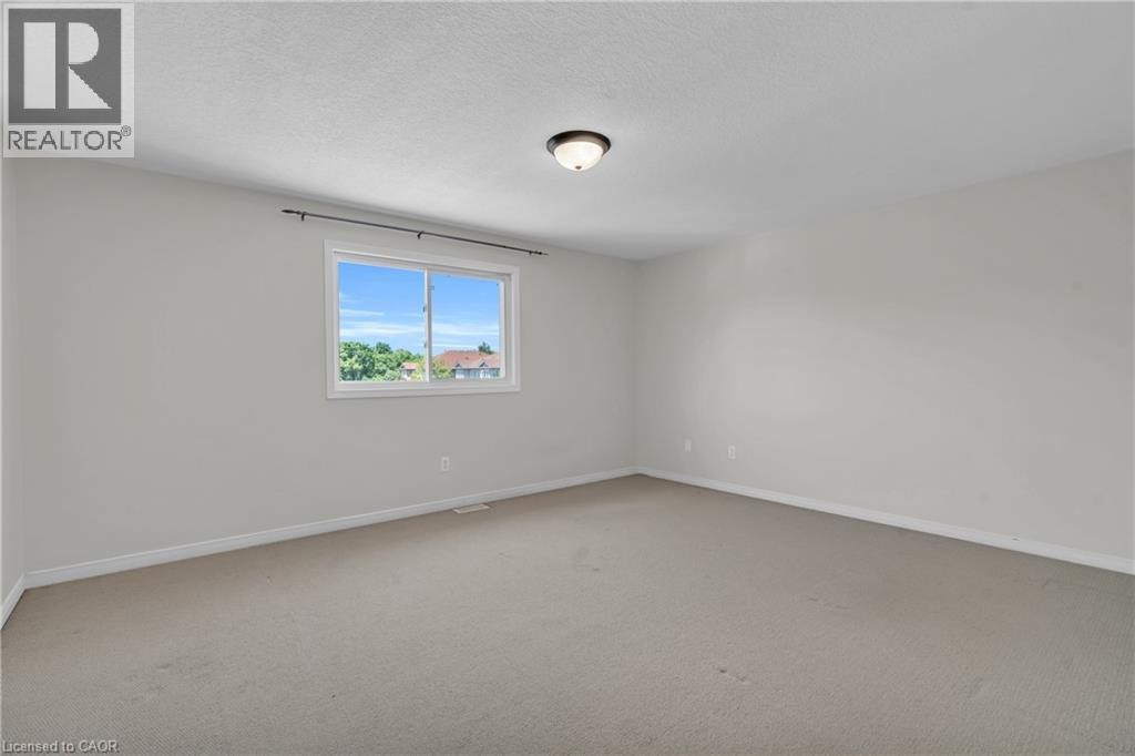 Carpeted flooring with light neutral wall tones, a ceiling-mounted light fixture, and a window with white trim - 50 Howe Drive Unit# 19B, Kitchener, ON