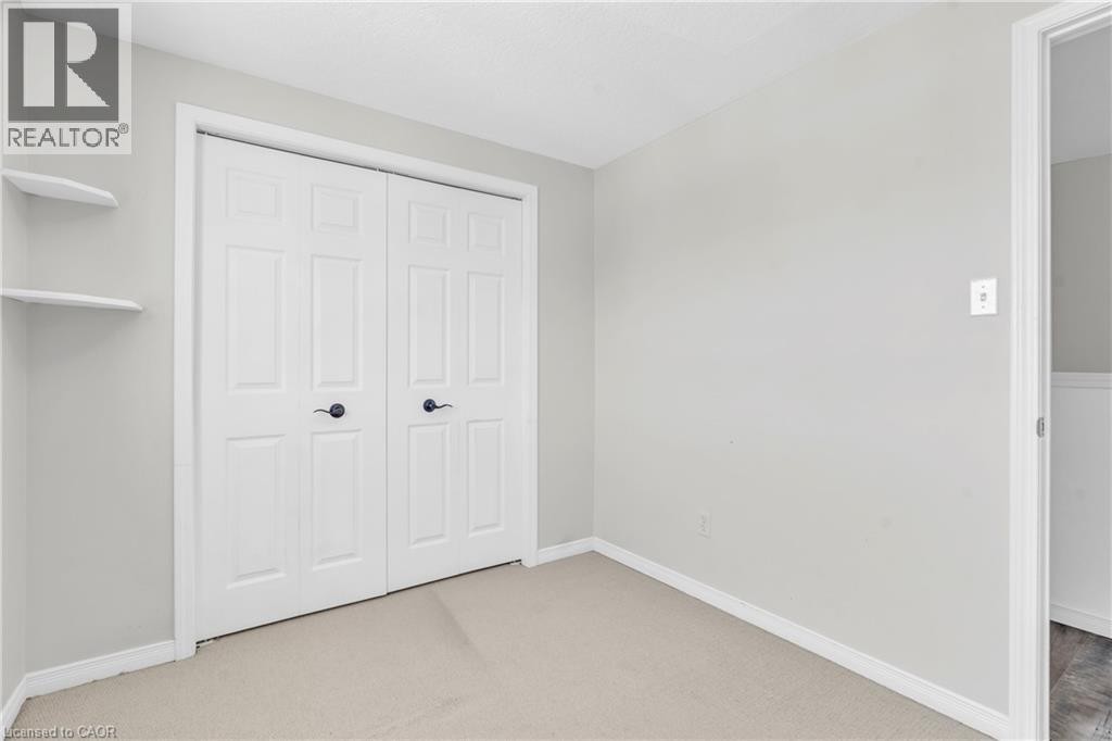 Neutral wall finishes, textured carpeting, white bi-fold closet doors, matte black door hardware, and built-in shelving - 50 Howe Drive Unit# 19B, Kitchener, ON
