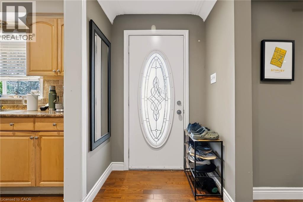 Entry door with decorative oval glass insert, wood-finish flooring, and crown molding - 1046 Shepherds Drive, Burlington, ON