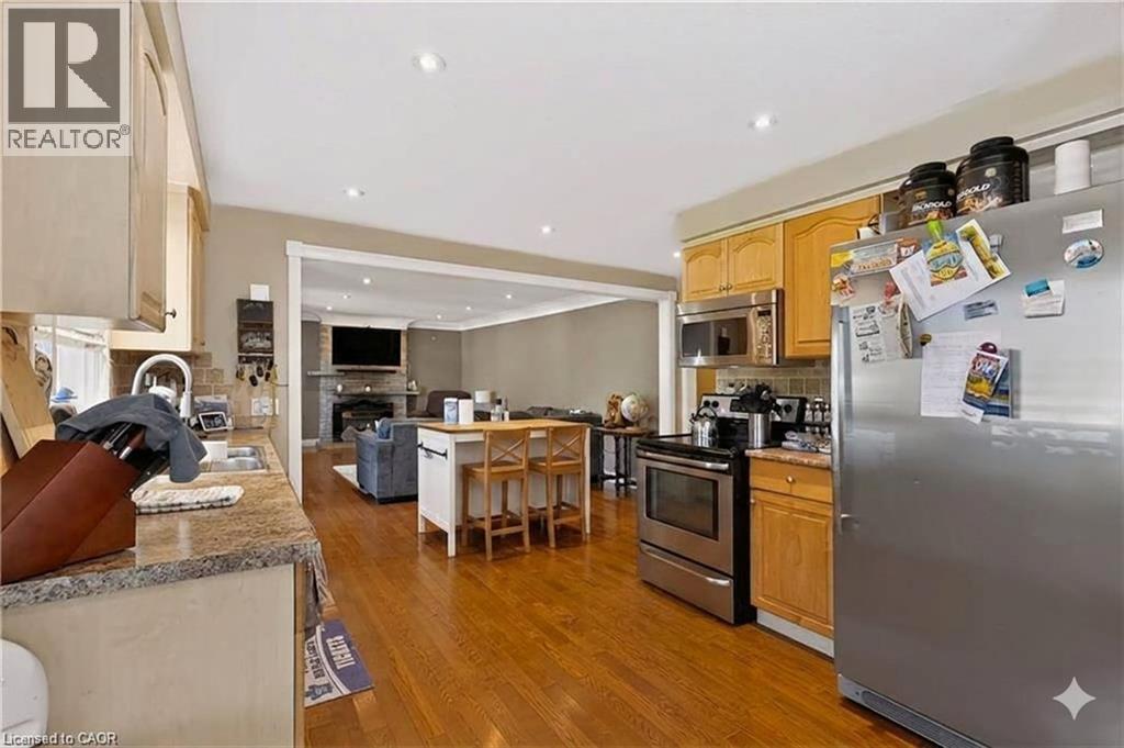 Kitchen with wood-finish flooring, stainless steel appliances, recessed lighting, and a kitchen island with seating - 1046 Shepherds Drive, Burlington, ON