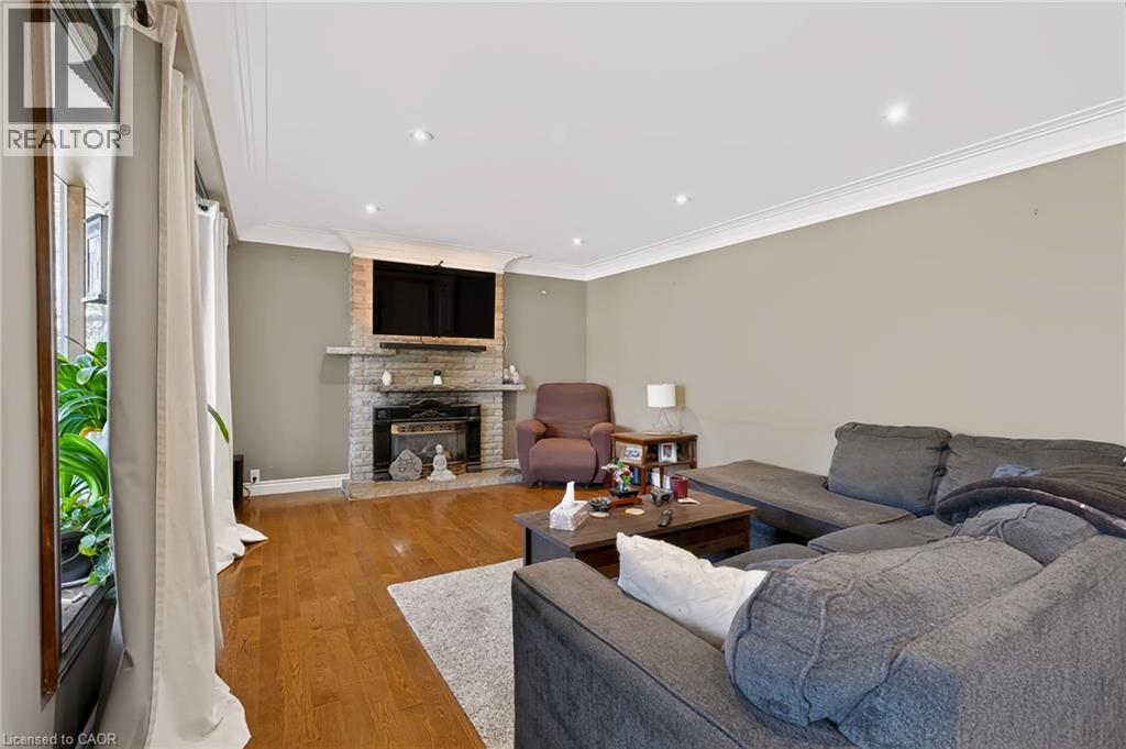 Stone-clad fireplace with mantel, recessed ceiling lighting, crown molding, and wood-finish flooring - 1046 Shepherds Drive, Burlington, ON