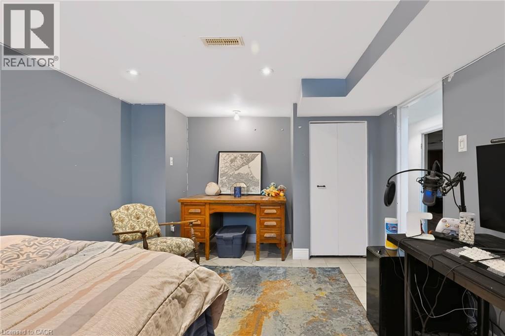 Recessed lighting illuminates the space, featuring a wood-finish desk, tiled flooring, and a built-in closet with bifold doors - 1046 Shepherds Drive, Burlington, ON