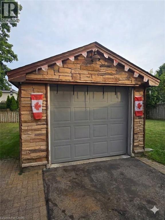 Stone facade garage with a panel garage door, asphalt driveway, and paver stone border - 1046 Shepherds Drive, Burlington, ON
