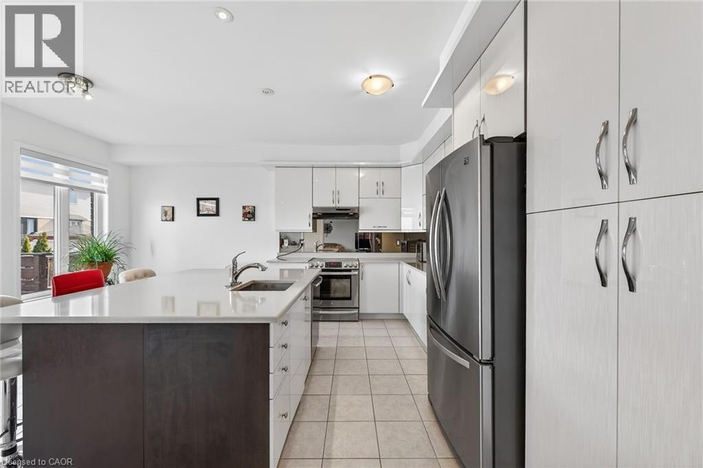 Kitchen with stainless steel appliances, a kitchen breakfast bar, light tile patterned flooring, and an island with sink - 97 Sirente Drive, Hamilton, ON