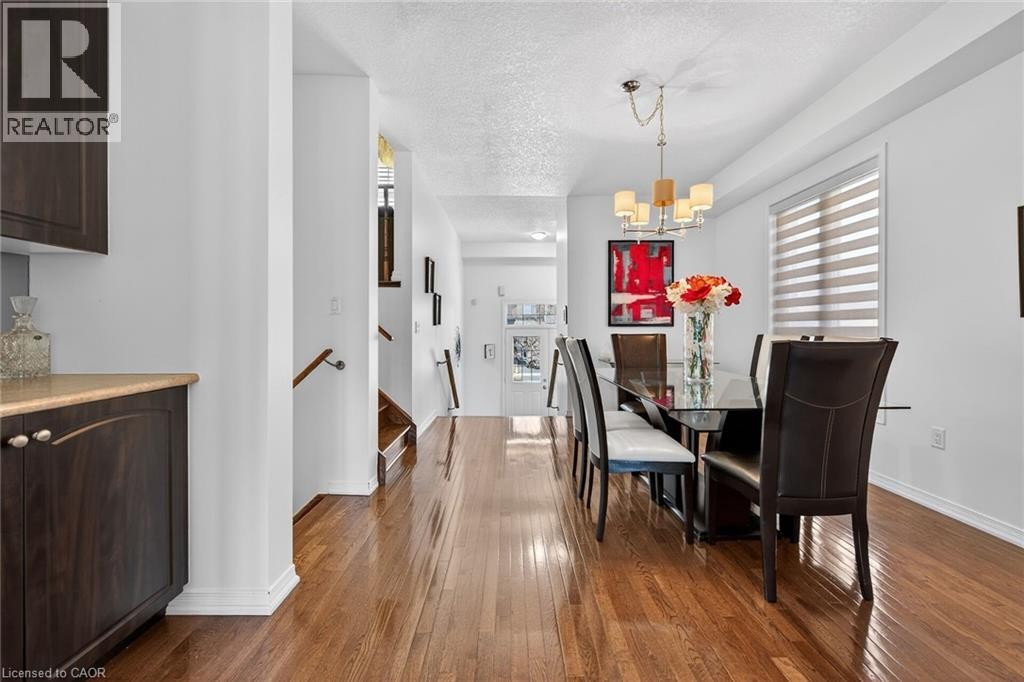Dining area featuring a textured ceiling, dark wood-style floors, plenty of natural light, and suspended lighting - 97 Sirente Drive, Hamilton, ON